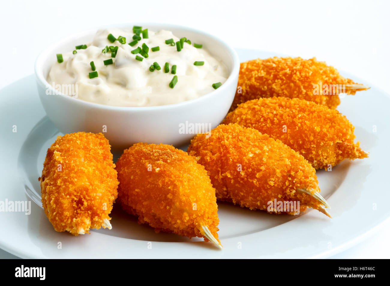 Plate of fried breaded surimi crab claws with bowl of tartar sauce isolated on white. Stock Photo