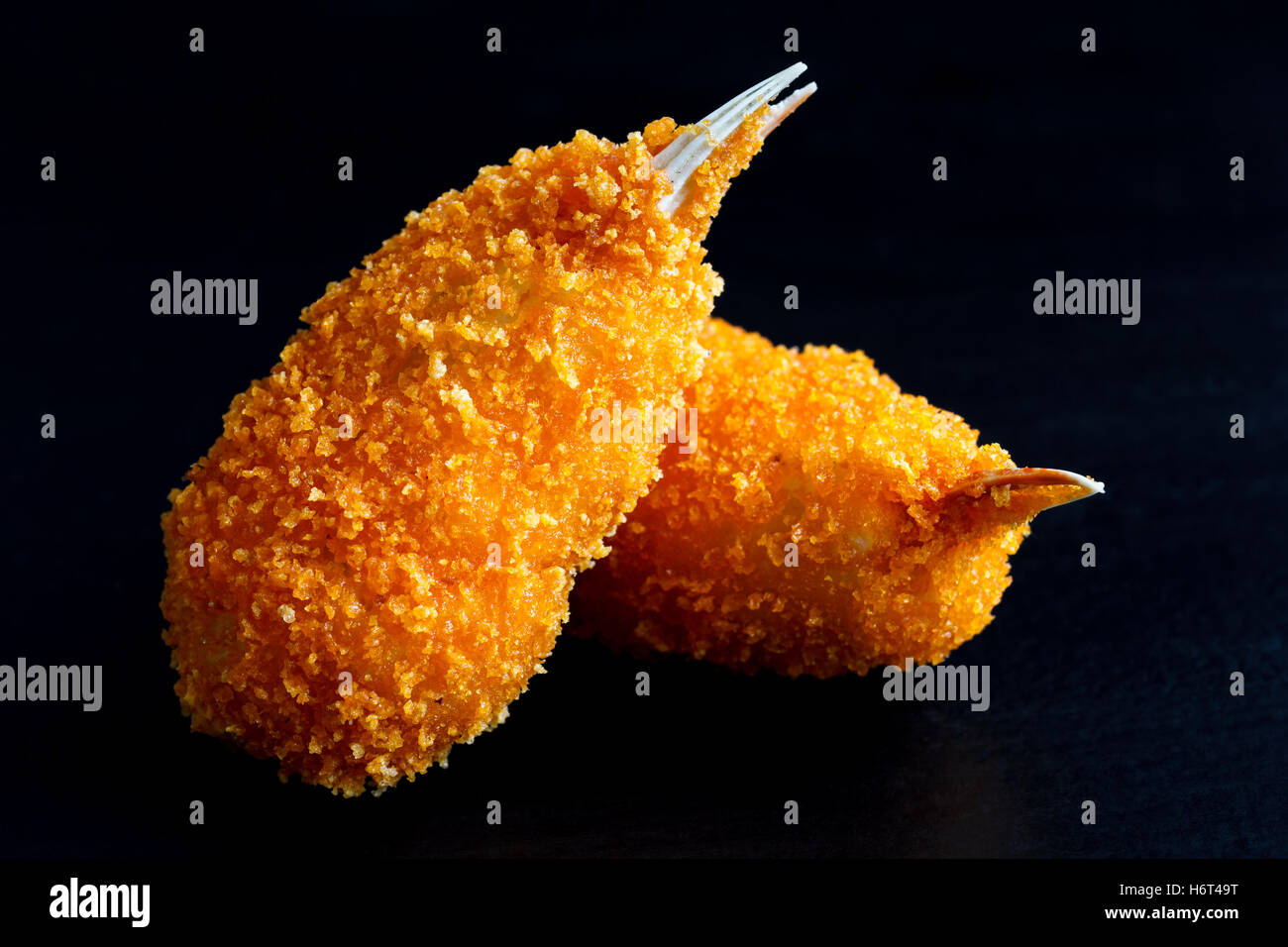Detail of two fried breaded surimi crab claws isolated on black in perspective. Stock Photo