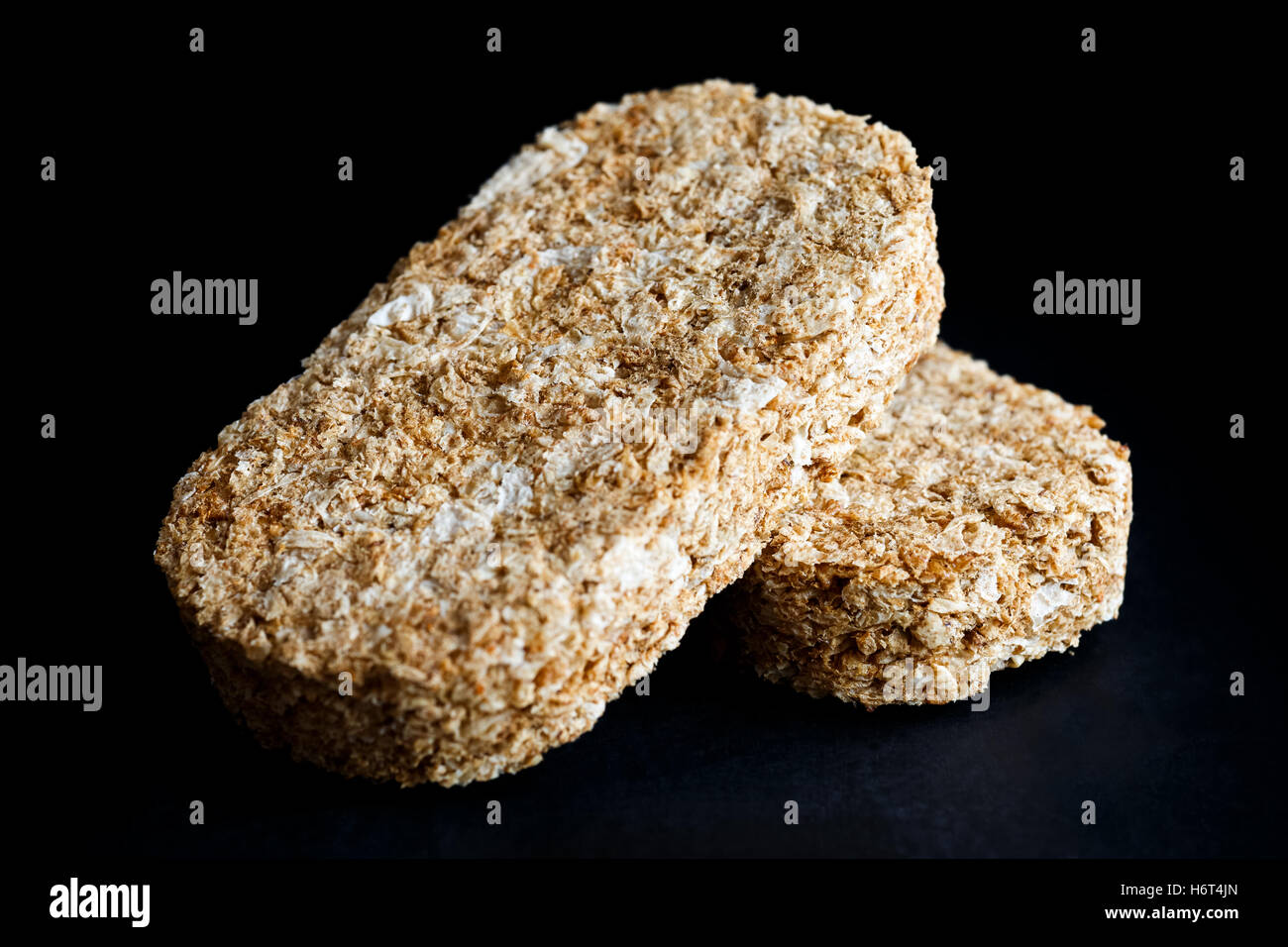 Two whole wheat breakfast biscuits isolated on black in perspective