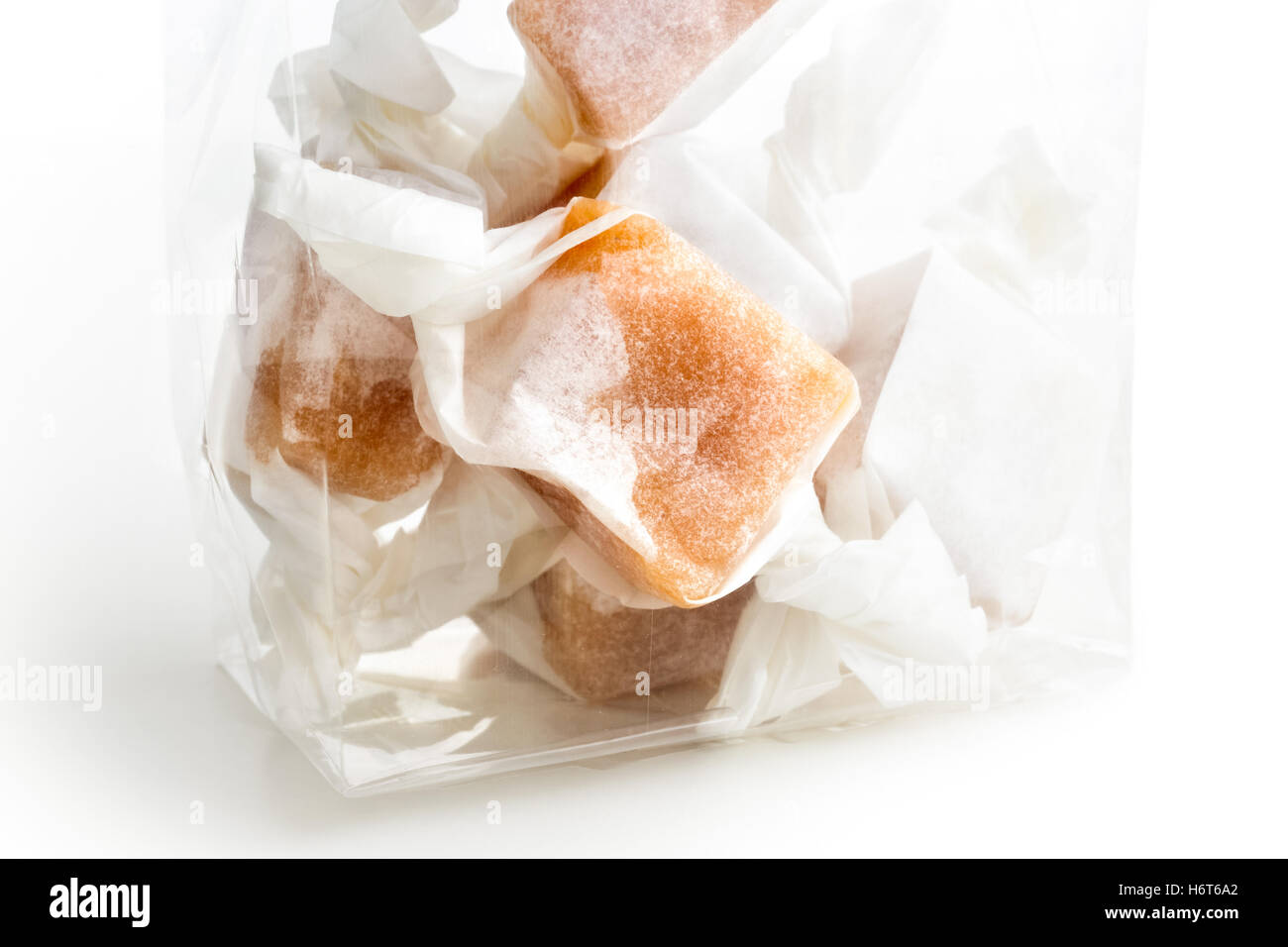 Detail of cellophane packet of wrapped caramel toffees on white. Stock Photo