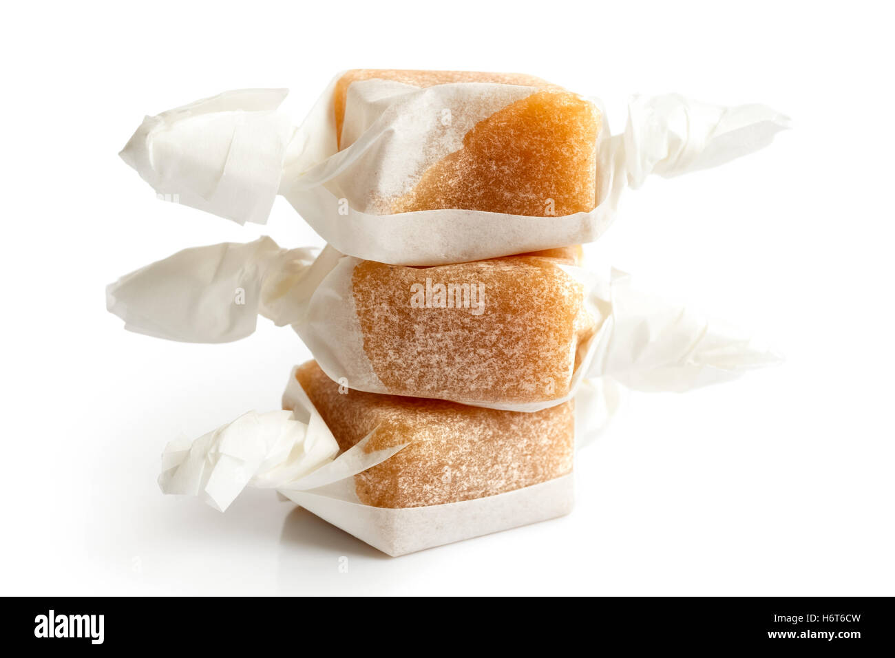 Stack of three wrapped vanilla caramel toffees isolated on white. Stock Photo