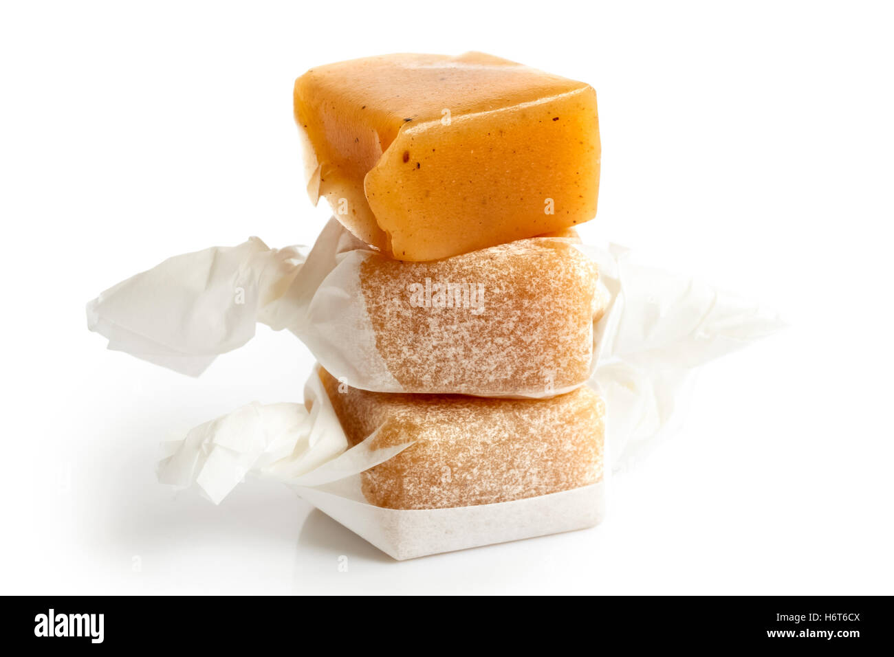 Stack of three luxury wrapped vanilla caramel toffees isolated. One unwrapped. Stock Photo