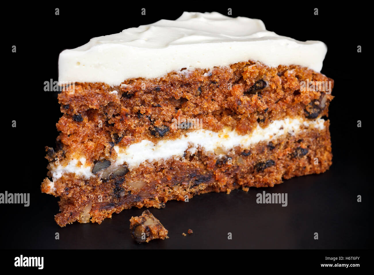 Slice of carrot cake with rich frosting. Isolated on black. Stock Photo