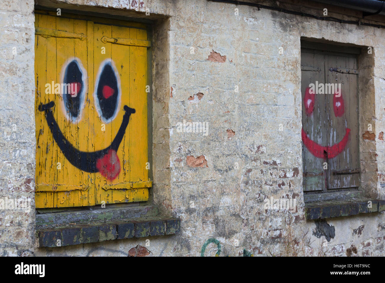 Smiling, happy faces painted onto the side of a derelict building Stock Photo