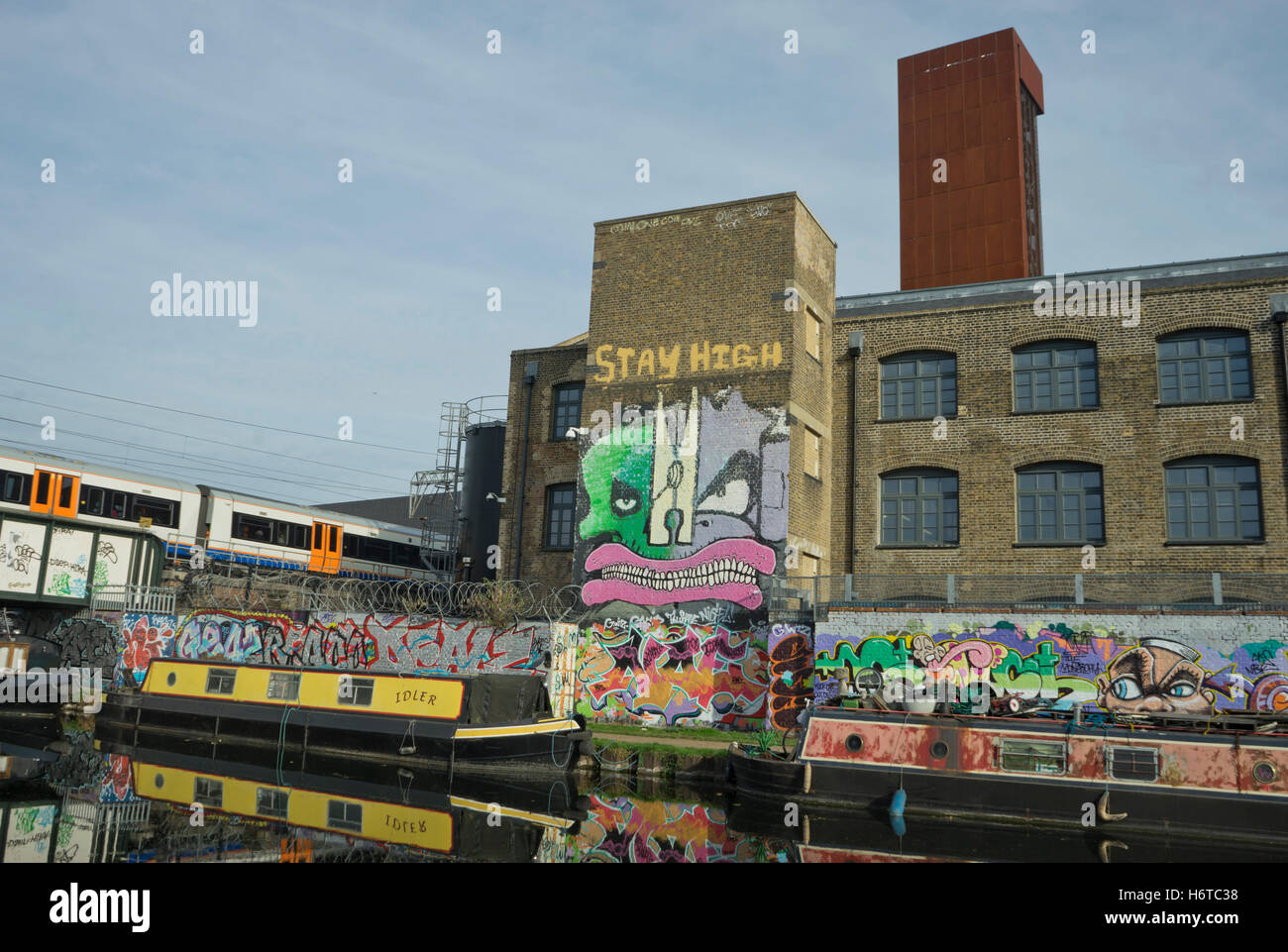Overground train drives past canal by artists studios and warehouses in Hackney Wick, which construction companies are threatening with eviction for development of new buildings and offices. London.UK Stock Photo