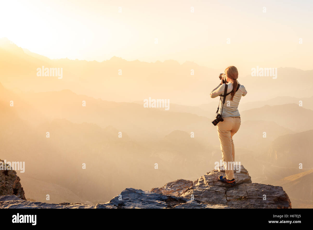 A woman is taking photos of Al Hajar Mountains in Oman at sunset Stock Photo