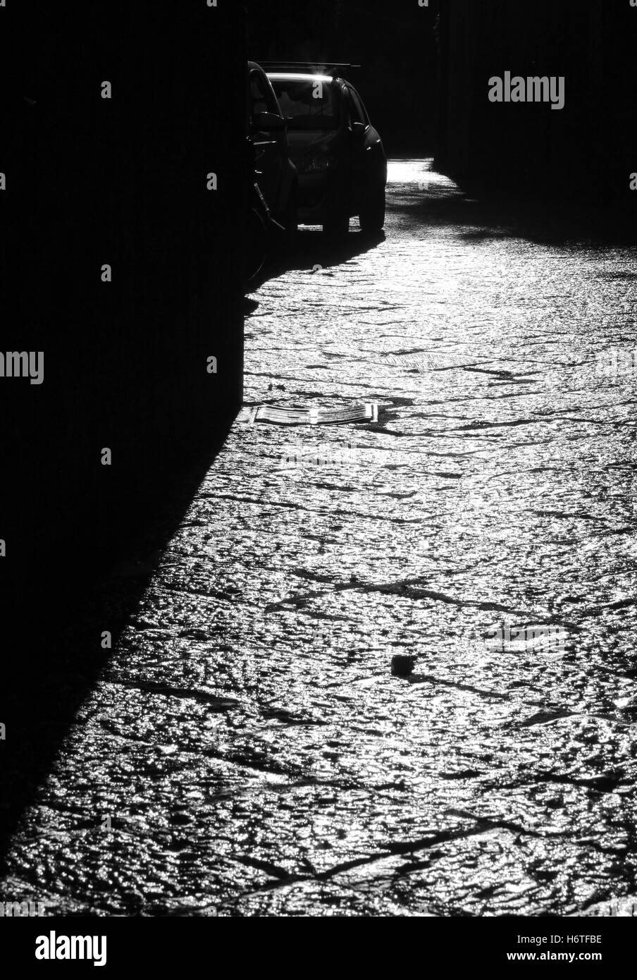 Long black shadows cast by sun early morning on road paved Italian Sorrento Roman interlocking grid stone slabs hard wearing. Stock Photo