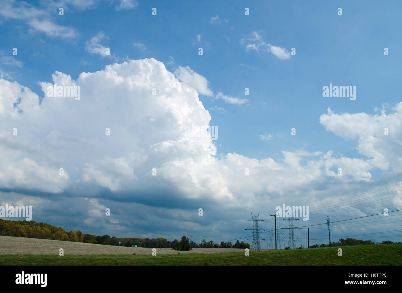 Giant high voltage power towers seem dwarfed by enormous cumulus clouds in northern Maryland. Stock Photo