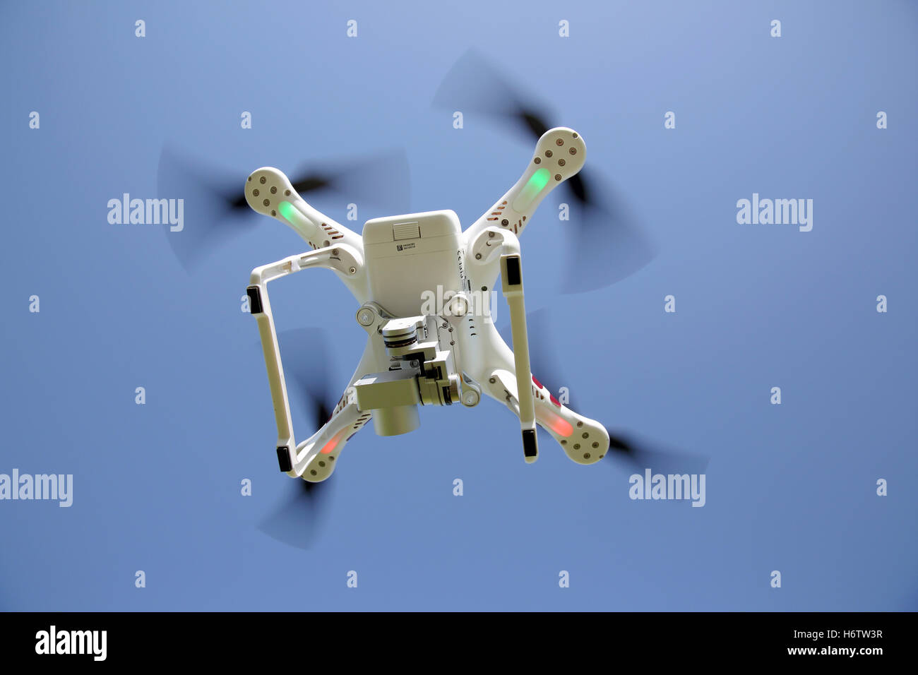 White drone quad copter with flying in the clear blue sky Stock Photo