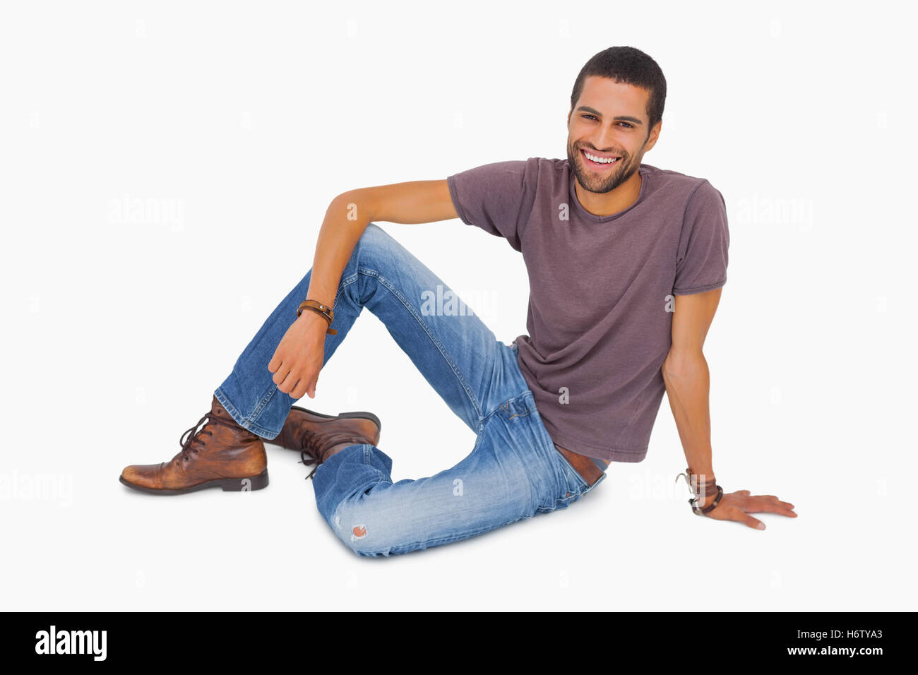 Smiling man sitting on floor on white background Stock Photo - Alamy