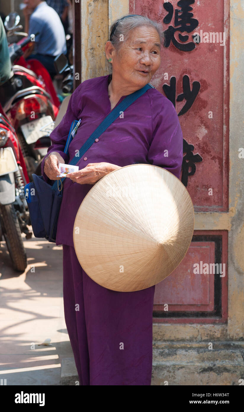 Woman with conical hat stood at the entrance to a temple Stock Photo