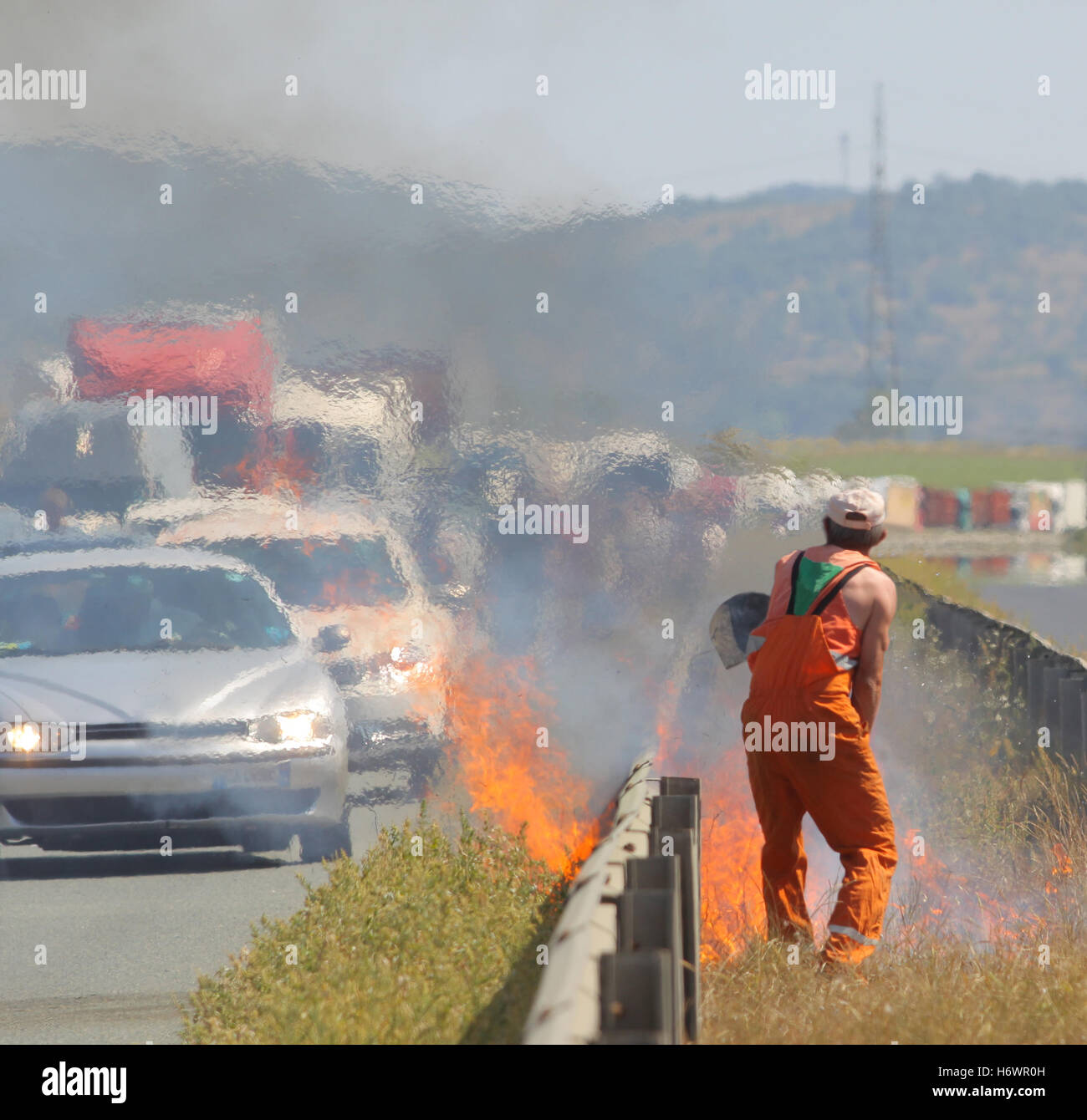 A road worker is putting up a fire caused traffic jam on a highway. Stock Photo