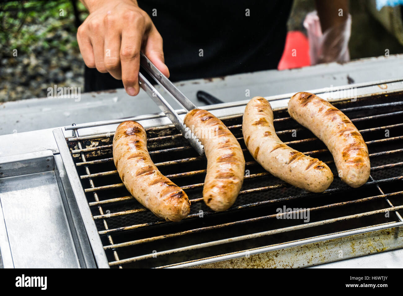 Fresh sausage and hot dogs grilling outdoors on a gas barbecue grill. Stock Photo