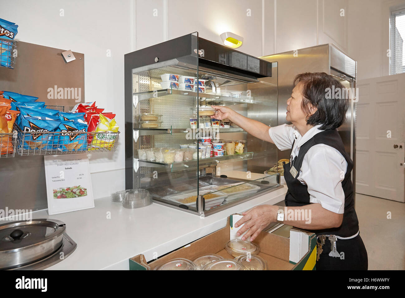 Kitchen worker, replenishing stock and tidying up in a works canteen