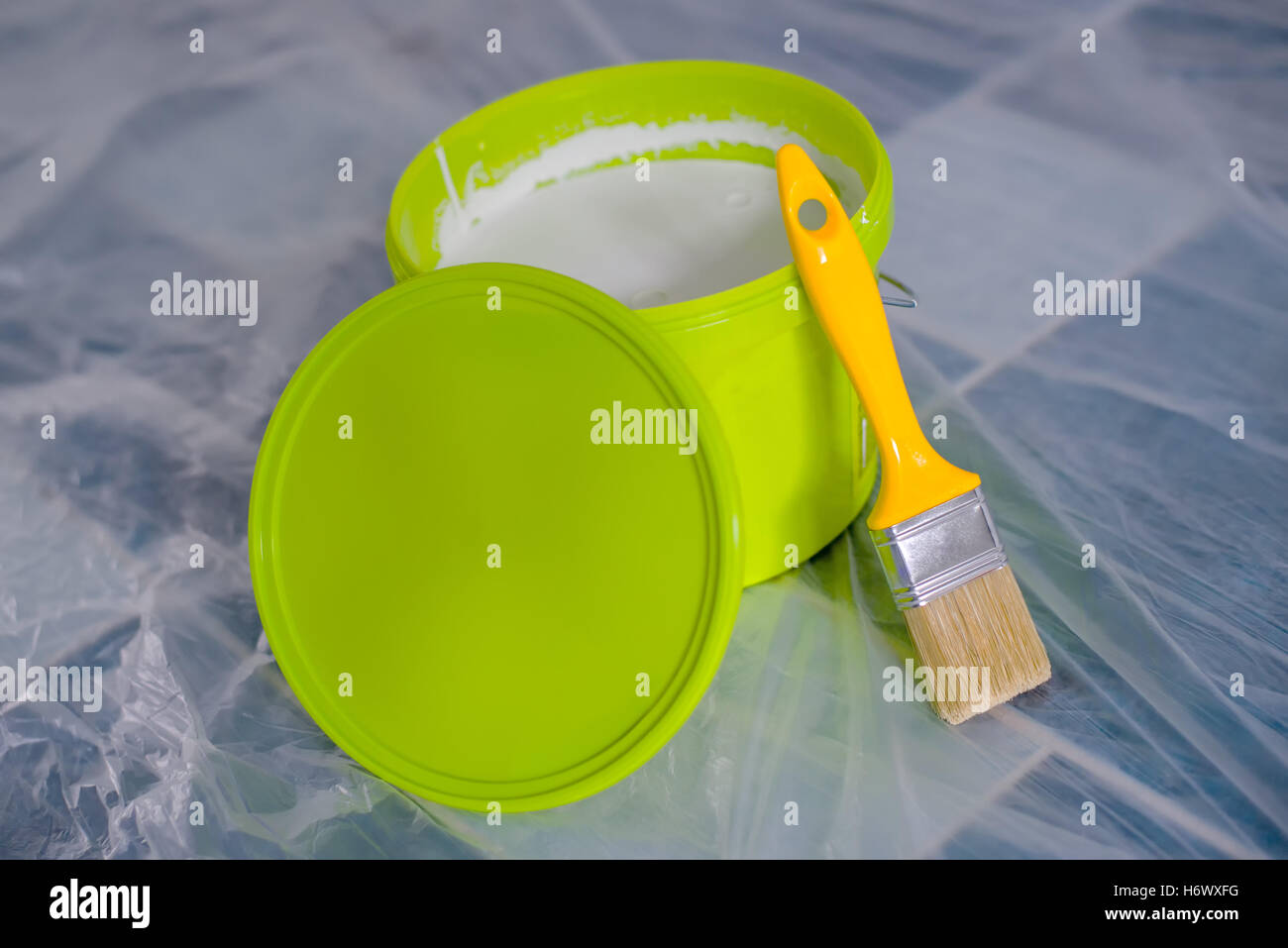 Yellow paint brush and green bucket on the floor, ready for housework project and walls redecoration Stock Photo