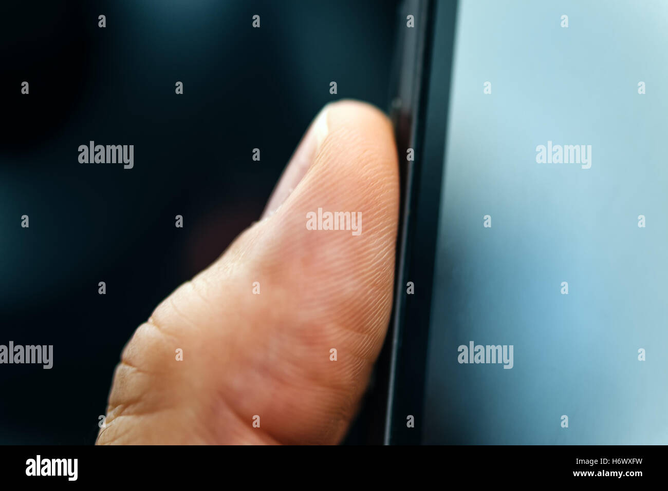 Unlocking smart phone with fingerprint sensor scan, close up with selective focus Stock Photo