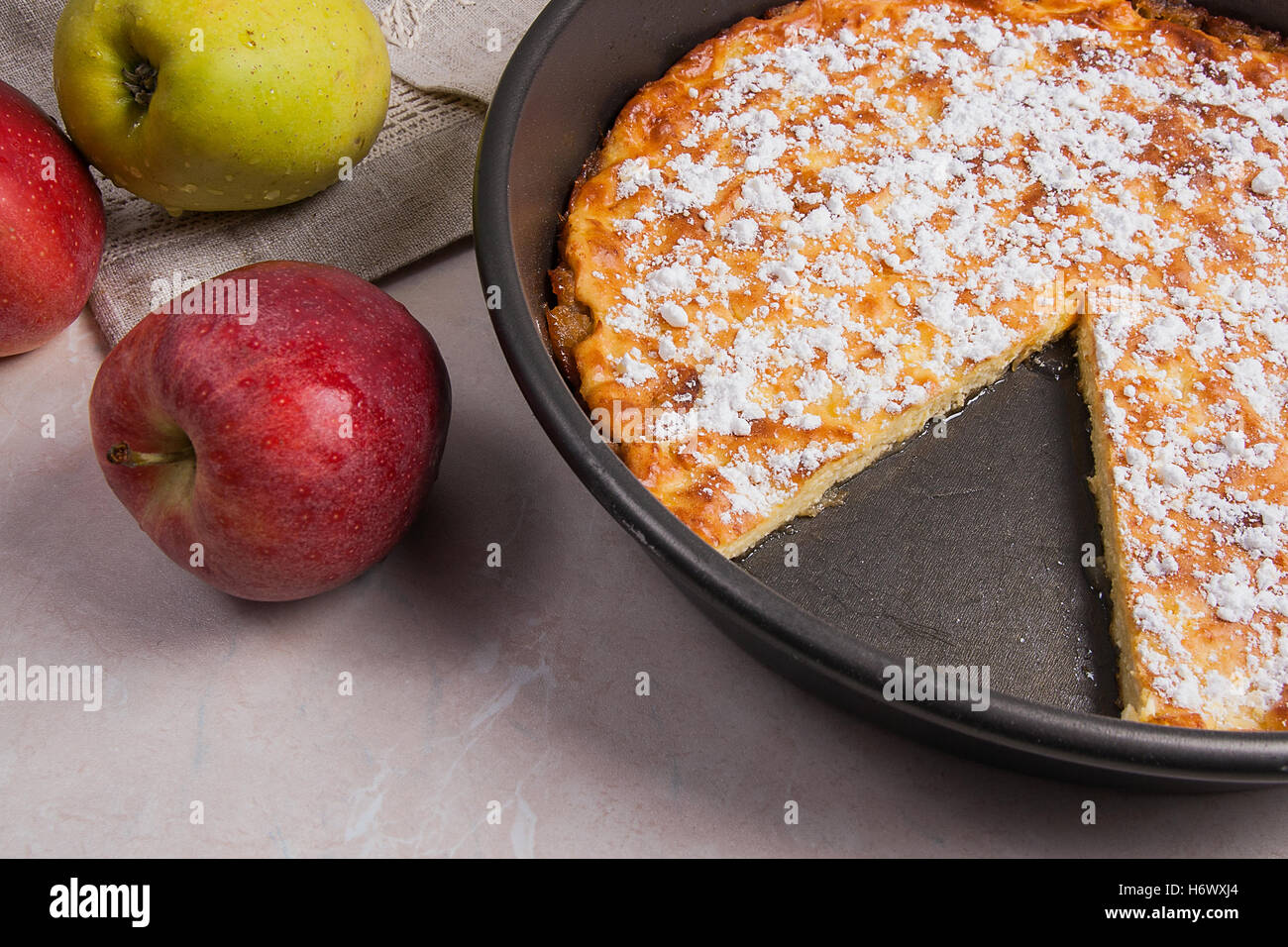 Homemade freshly baked apple pie with apples. Dessert ready to eat. Several organic red and green apples in the background. Stock Photo