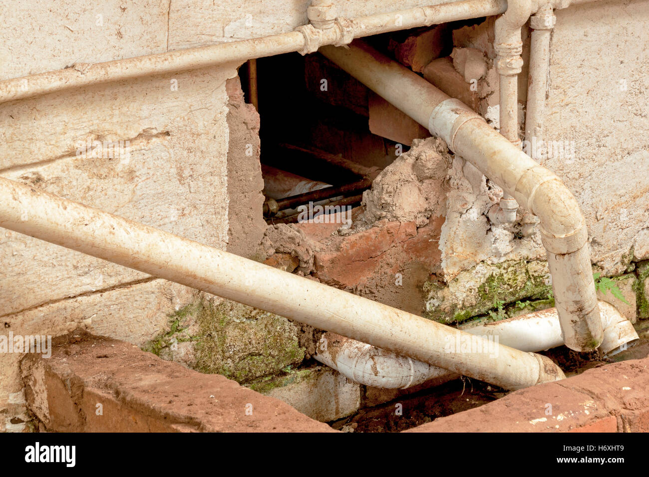 Close up of broken wall plumbing pipes and drain requiring maintenance and repair Stock Photo