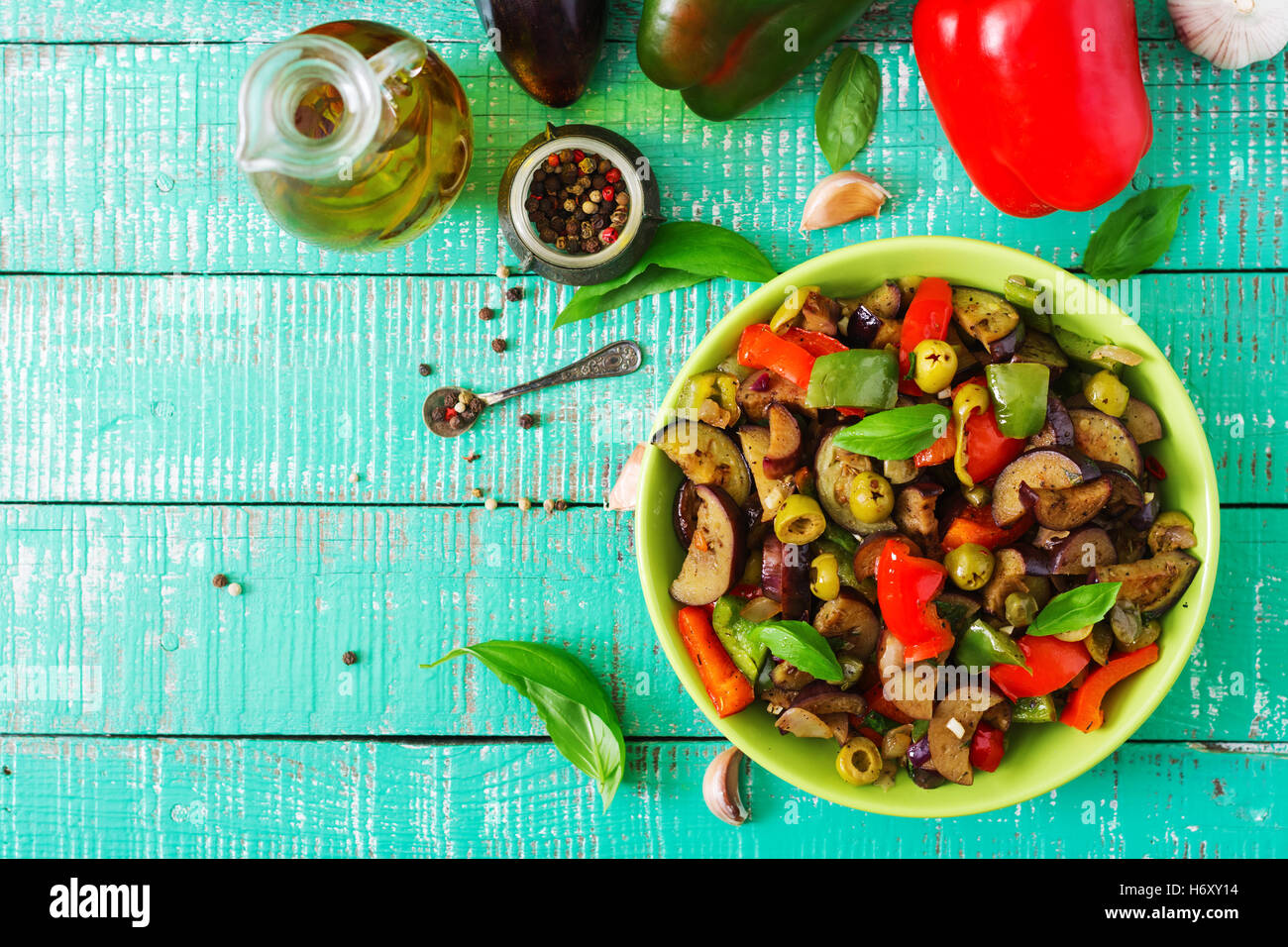 Hot spicy stew eggplant, sweet pepper, olives and capers with basil leaves. Top view Stock Photo