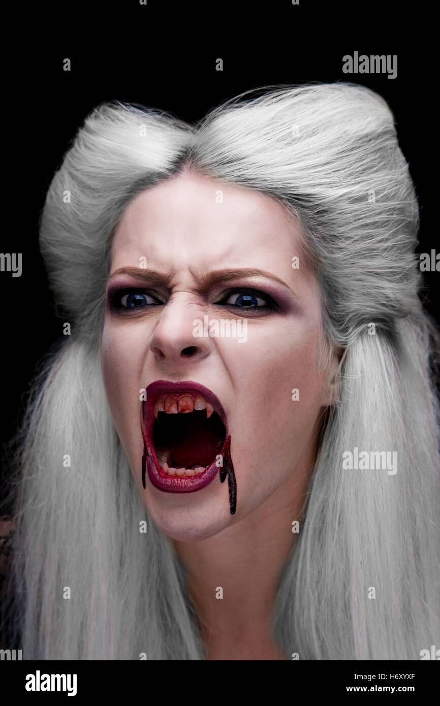 Beautiful blond girl vampire is screaming. The blood is on the mouth. Stock Photo