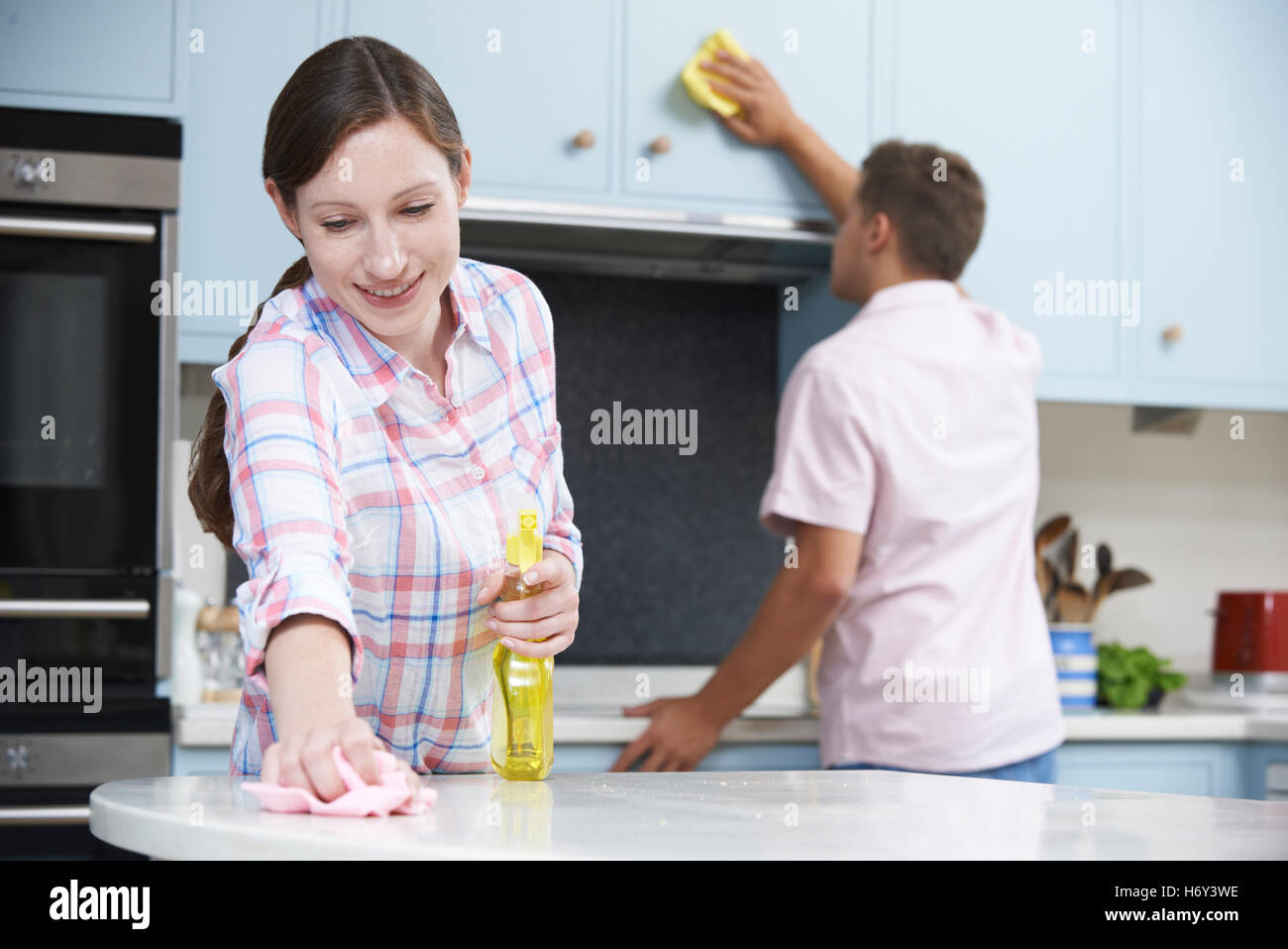 Couple Cleaning Kitchen Surfaces And Cupboards Together Stock Photo