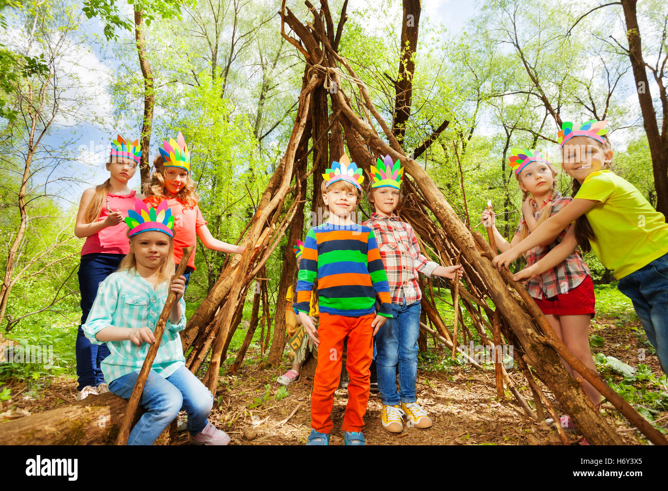 Happy kids building Injun's wigwam in the forest Stock Photo