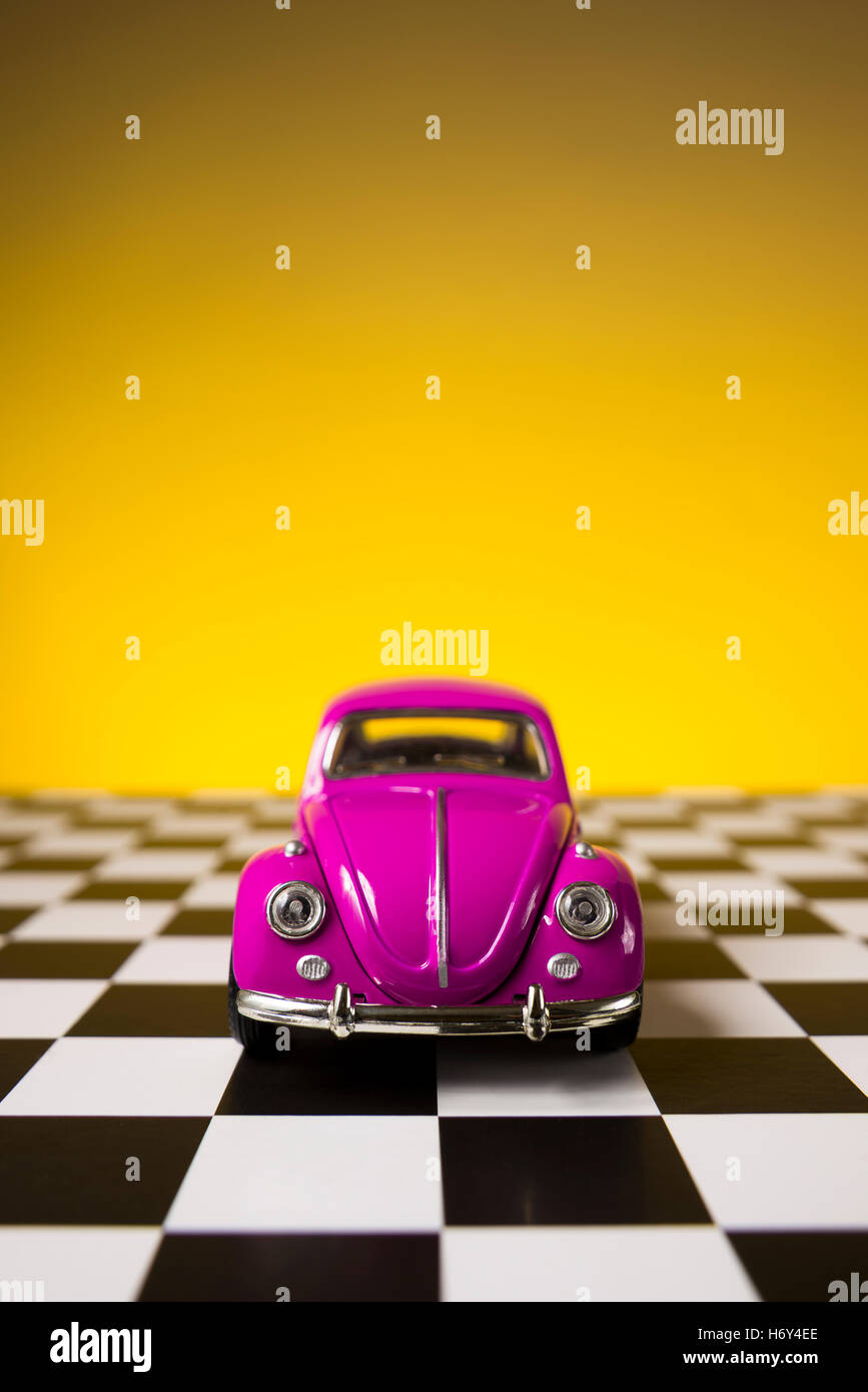 Izmir, Turkey - November 21, 2015. Still life shot of a Pink volkswagen beetle on a yellow background and checked floor. Stock Photo