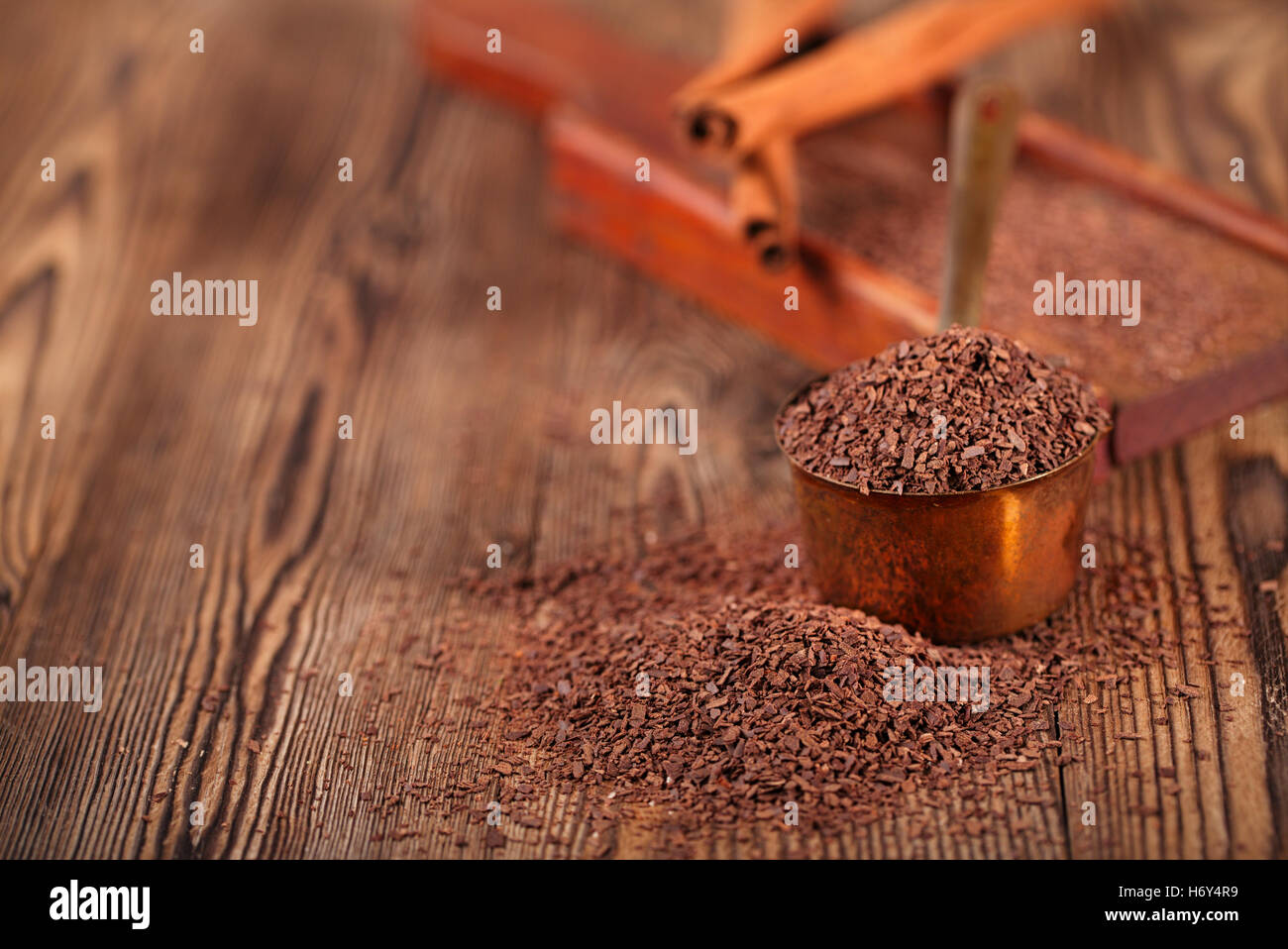 grated dark chocolate in copper measure pan on wooden background Stock