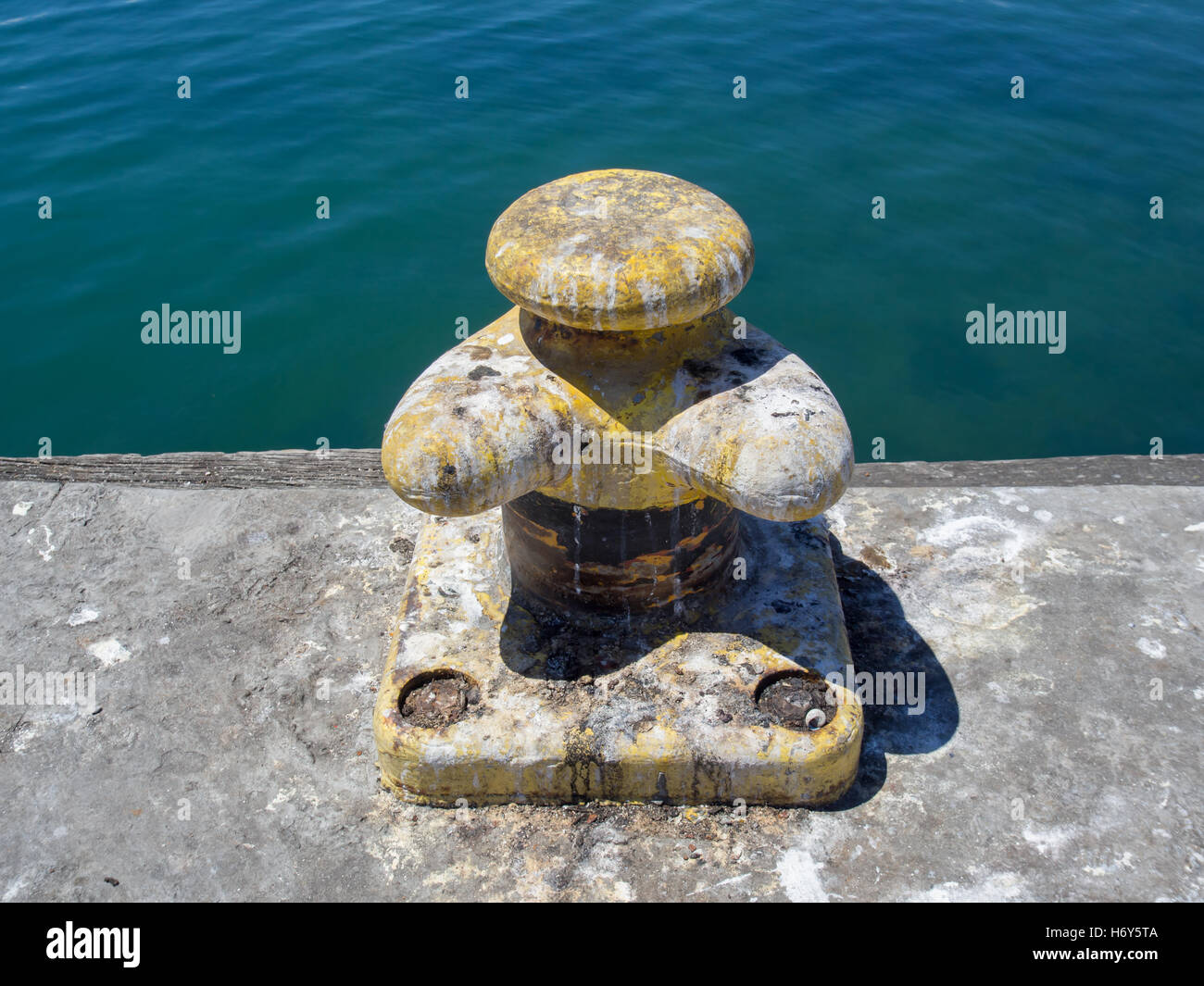 Yellow boat bollard covered in seagull droppings at the harbour of Lambert's Bay, South Africa. Stock Photo