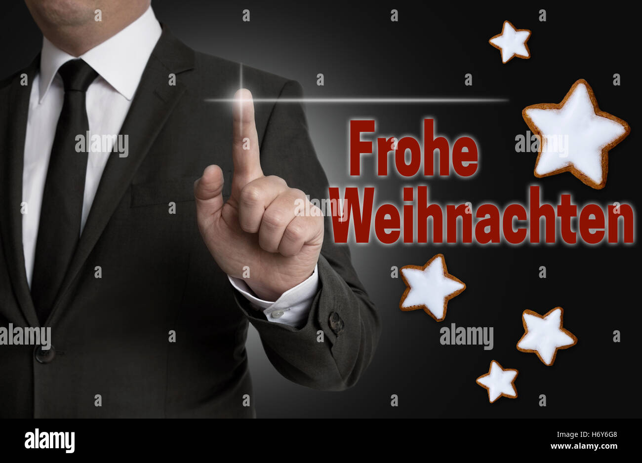 Frohe Weihnachten (in german Merry Christmas) touchscreen is operated by a businessman. Stock Photo