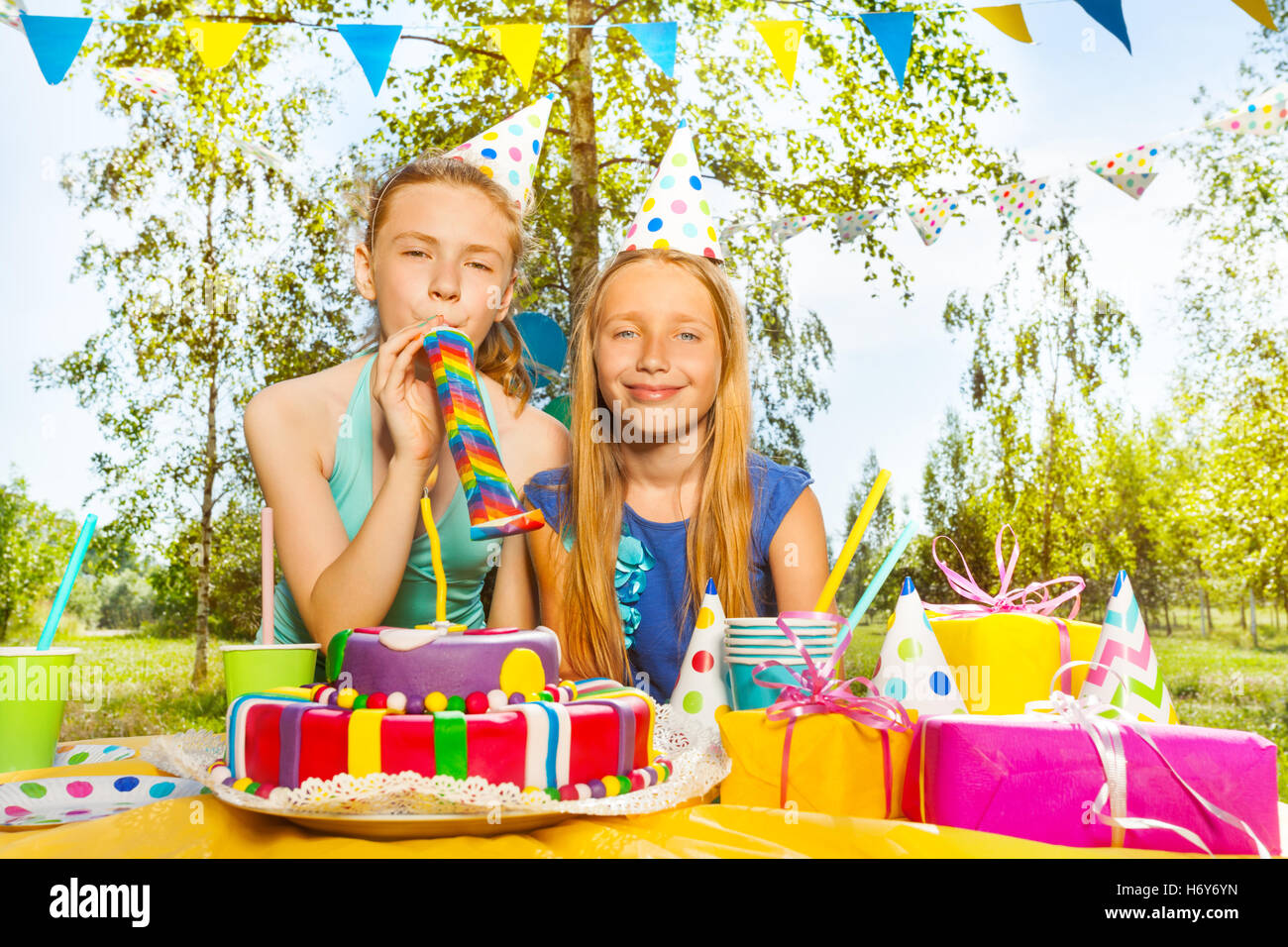 Two happy young girls playing with party blowers Stock Photo - Alamy