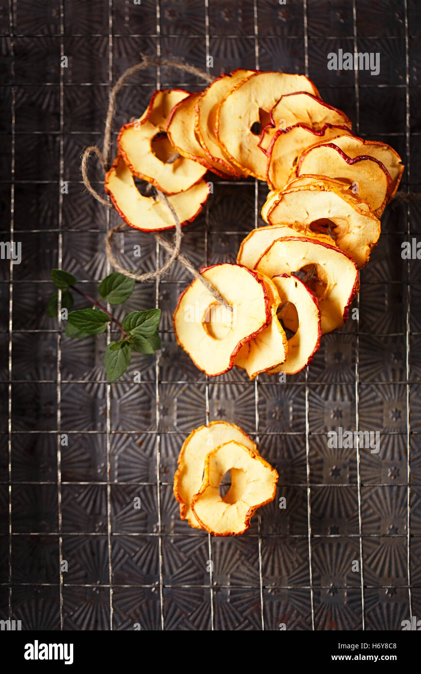Dried apple slices hanging on string with dark metal backdrop Stock