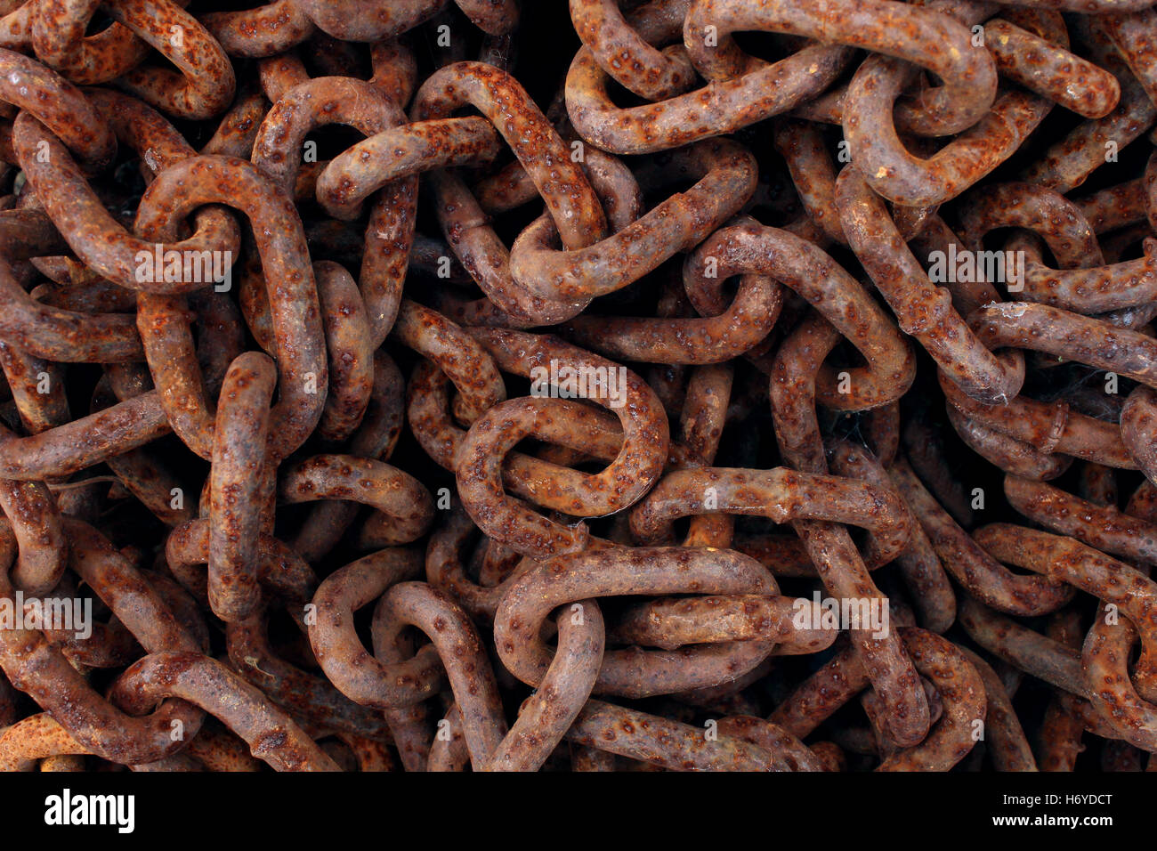 Rusted old iron chains background as a stack of oxidized decaying metal links as an abstract symbol of industrial aging or corrosion. Stock Photo