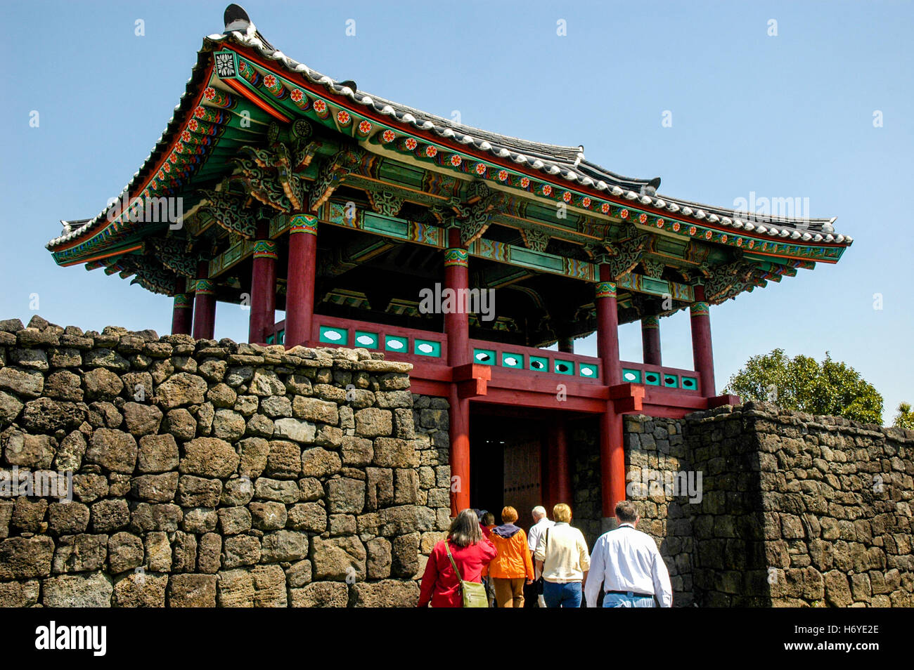 visitors entering through ornate oriental entrance gate of seongeup folk village. jeju (cheju). sth korea Stock Photo