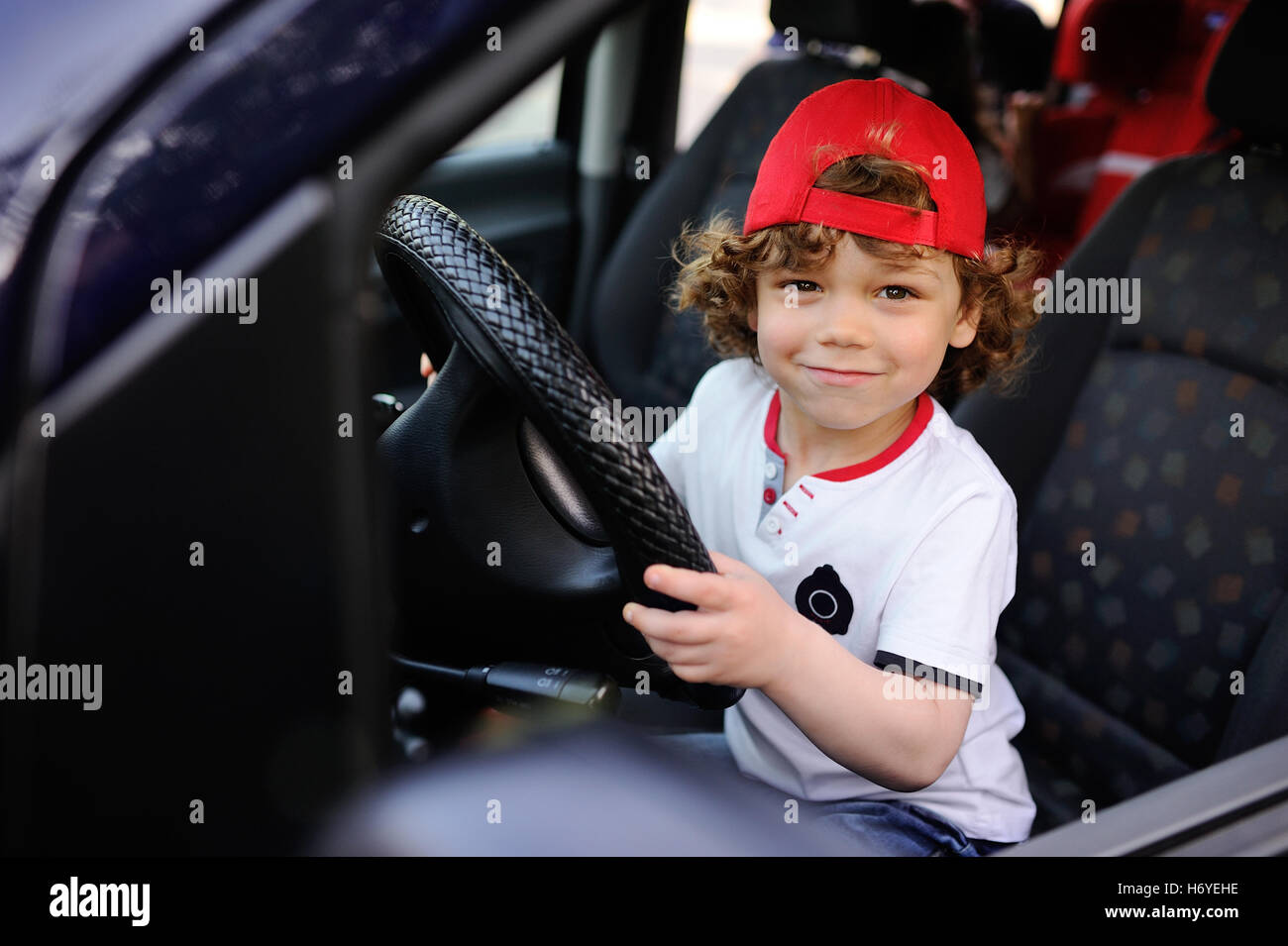 child with curly hair and a red cap 
