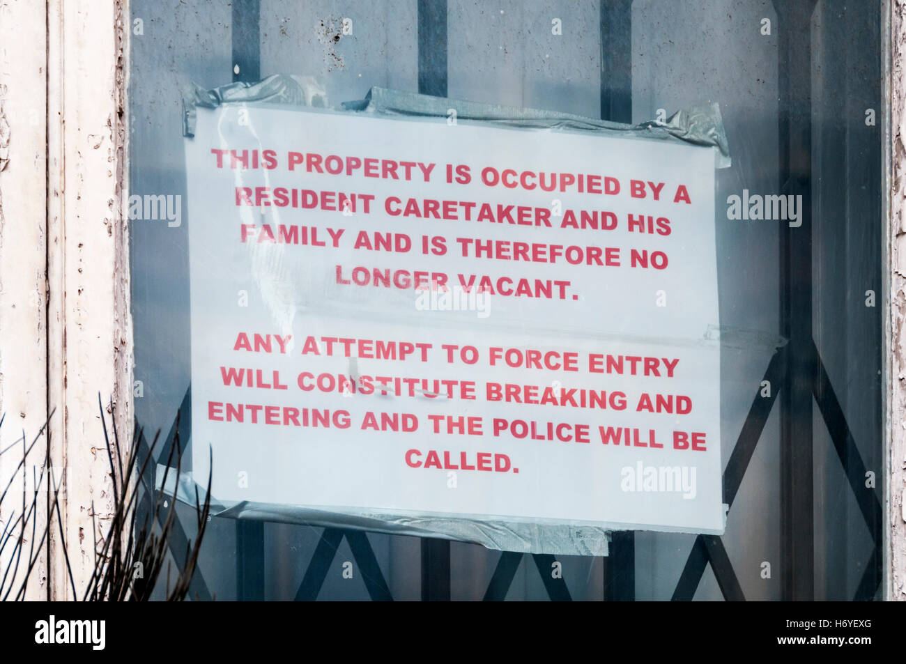 A sign in a window warns that a building is occupied by a resident caretaker and so cannot be squatted. Stock Photo