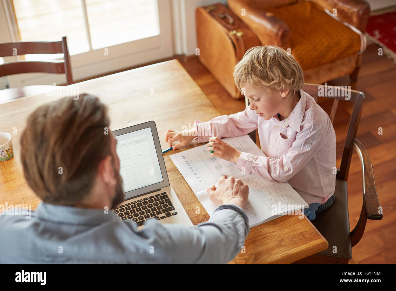 Father helping son with homework in home office Stock Photo - Alamy