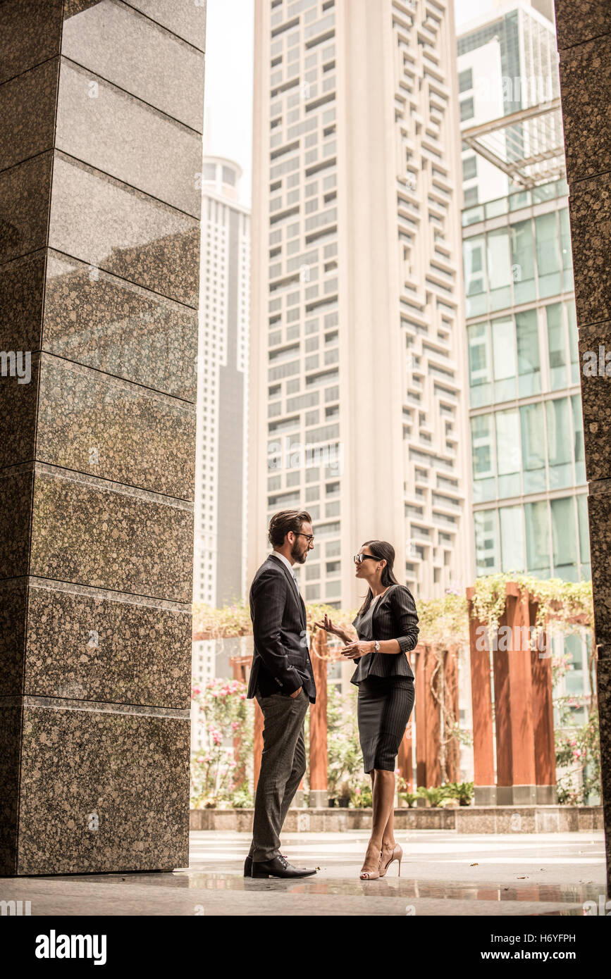 Businessman and woman talking outside office, Dubai, United Arab Emirates Stock Photo