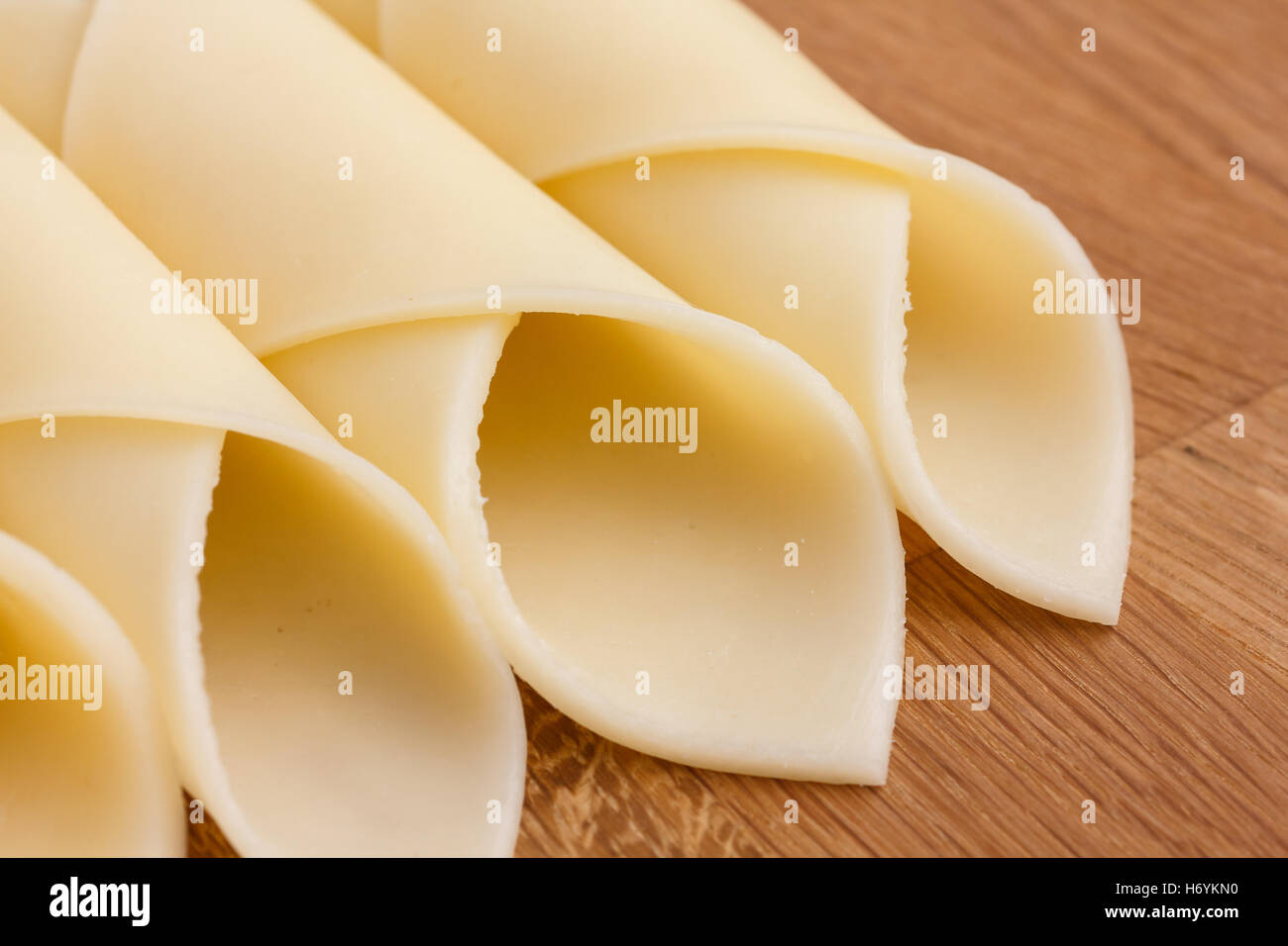 Wrapped yellow cheese slices arranged on a wood surface. Stock Photo