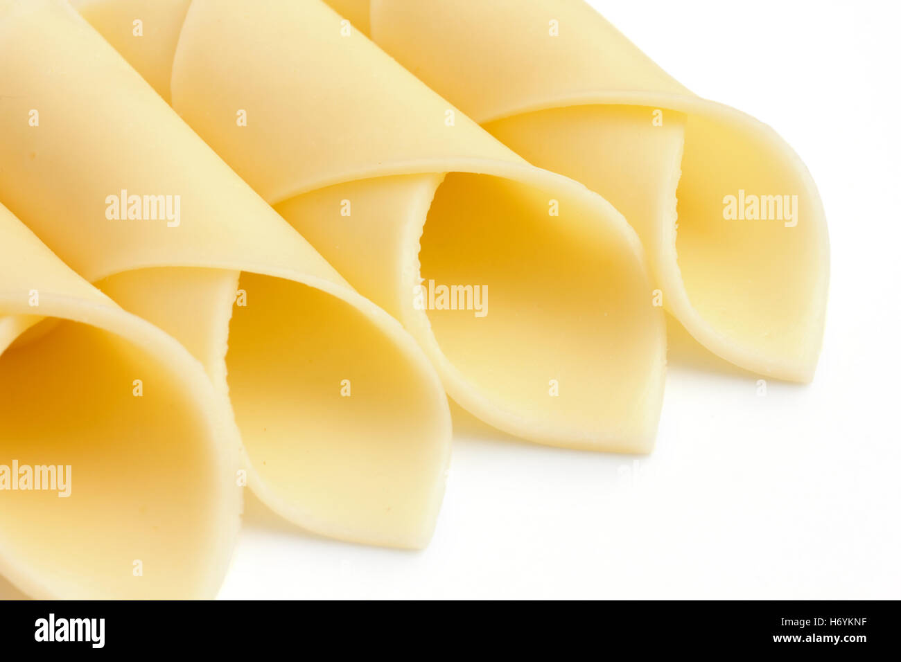 Wrapped yellow cheese slices arranged on a white surface. Stock Photo