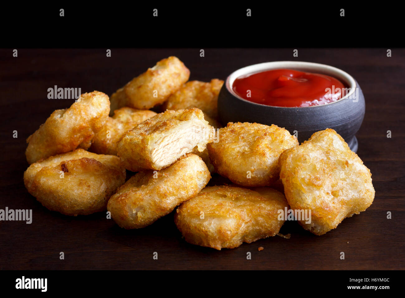Pile of golden deepfried battered chicken nuggets with empty rustic
