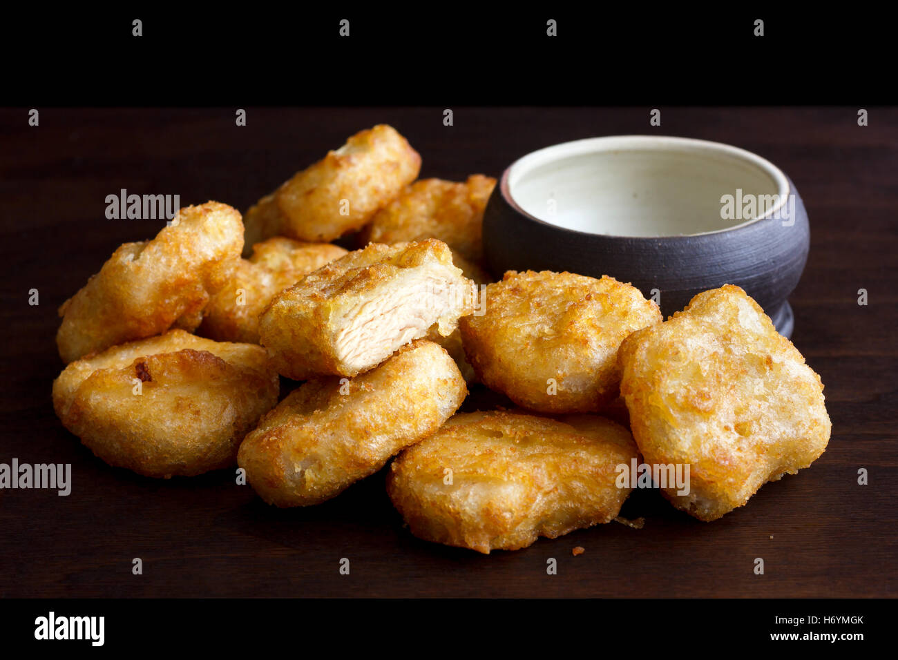 Pile of golden deepfried battered chicken nuggets with empty rustic