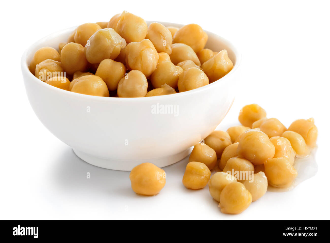 Cooked chickpeas in white bowl on white. Spilled chickpeas. Stock Photo