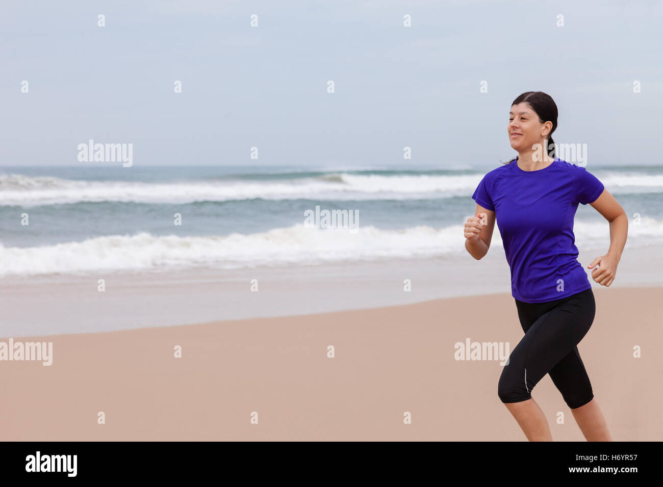 Female athlete running at the beach on an Autumn day. Stock Photo