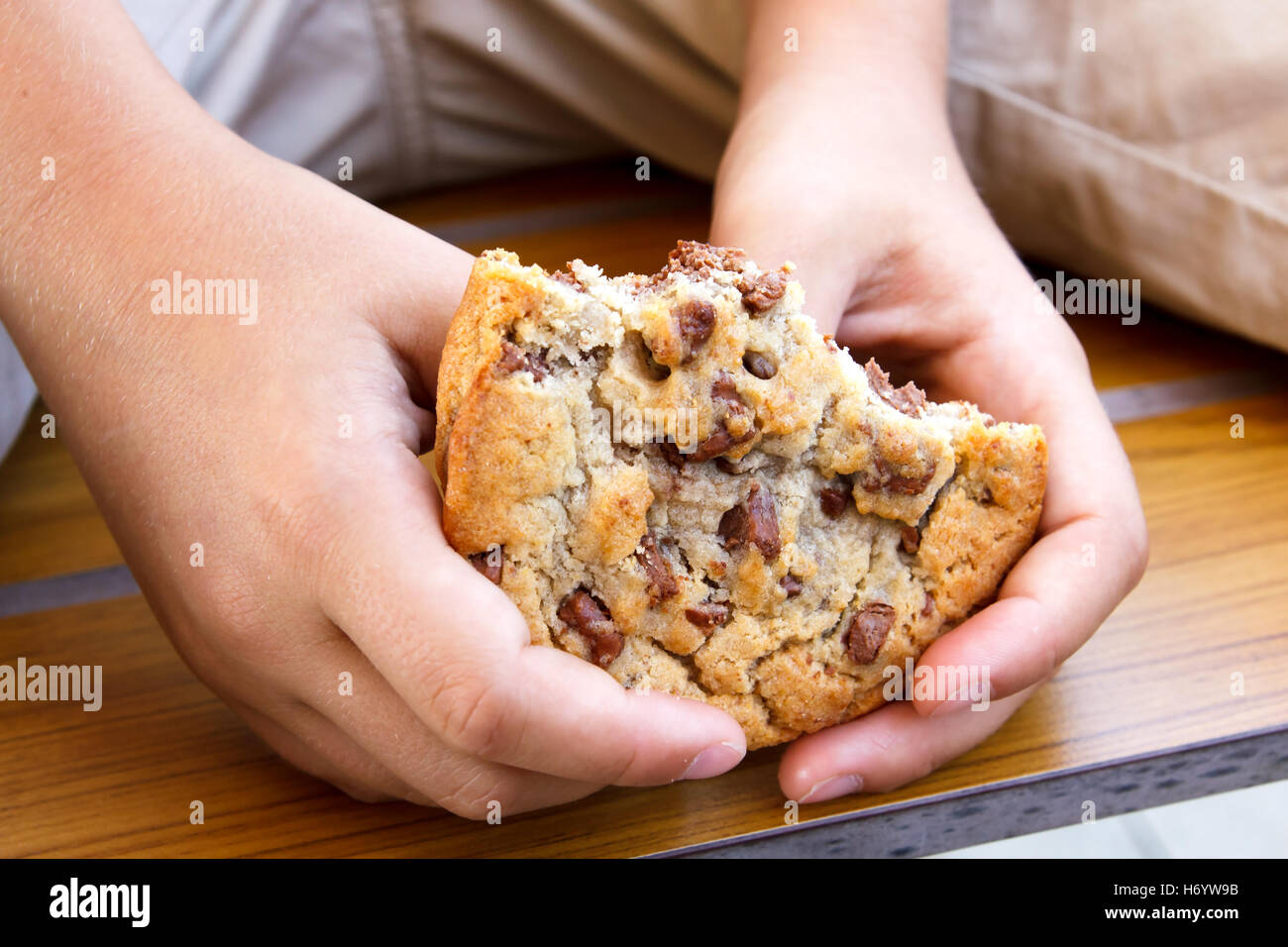 Child holding large half eaten homemade chocolate chip cookie. Stock Photo