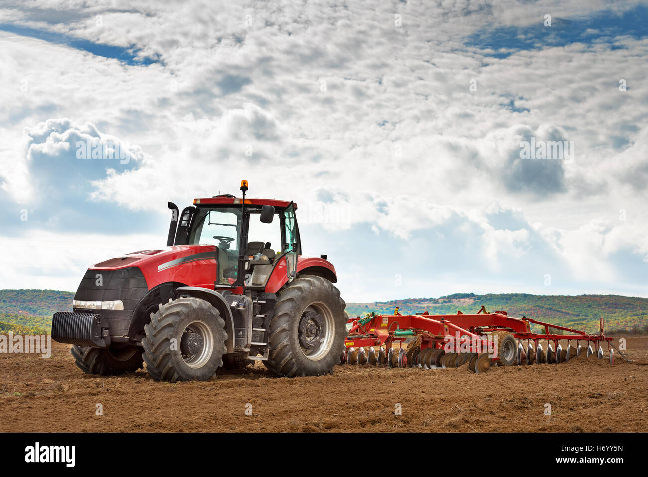 modern red tractor in the agricultural field. Stock Photo