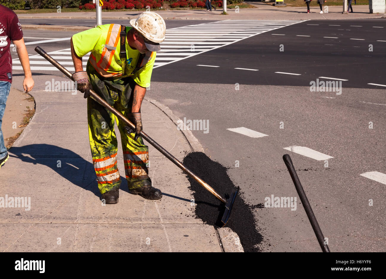 A construction worker fixing a curb with asphalt in Ottawa, Ontario, Canada. Stock Photo