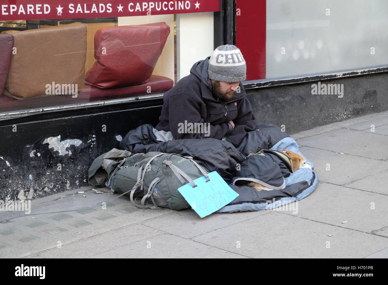 Homeless man in a street outside a cafe. Stock Photo