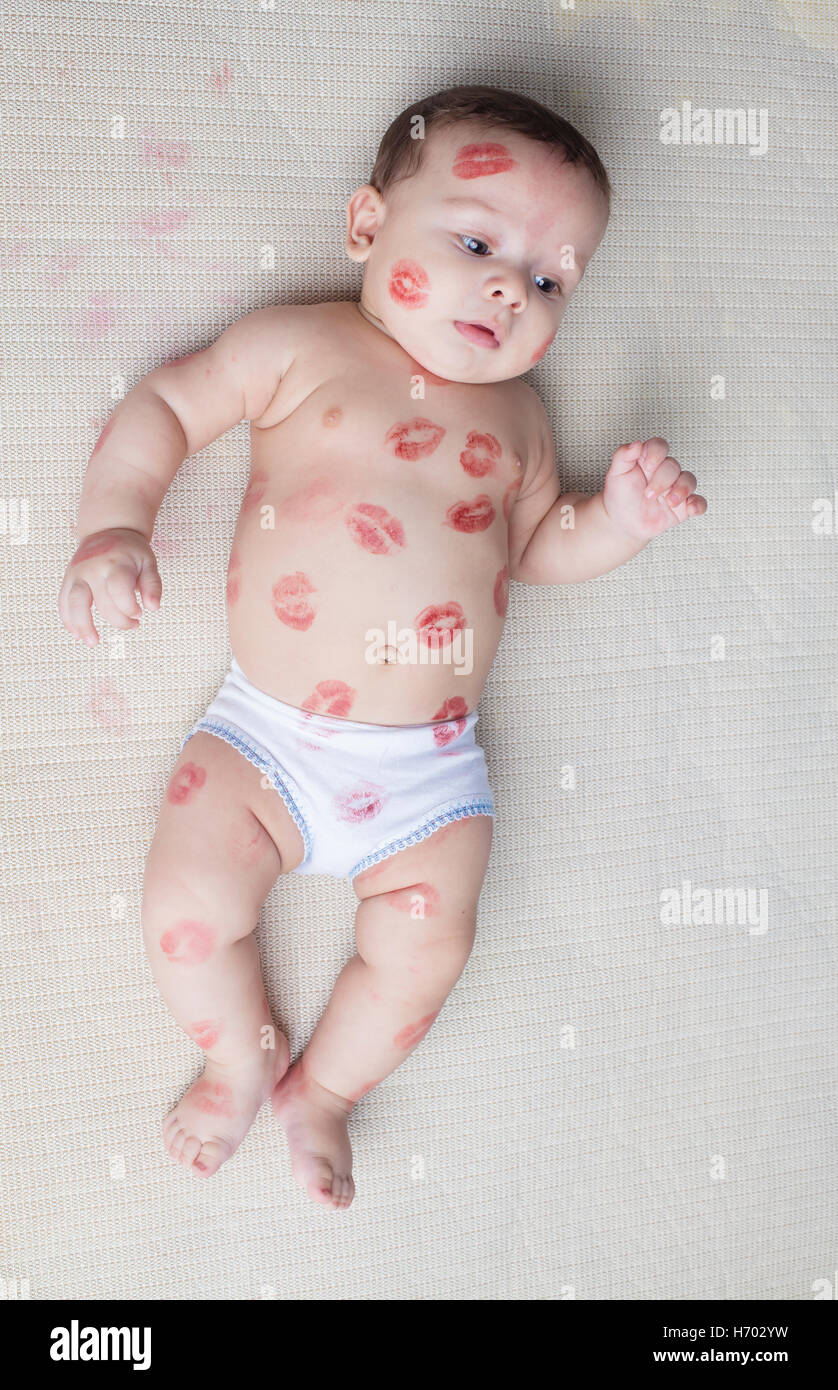 Small boy laying on fabric kissed with red lips Stock Photo