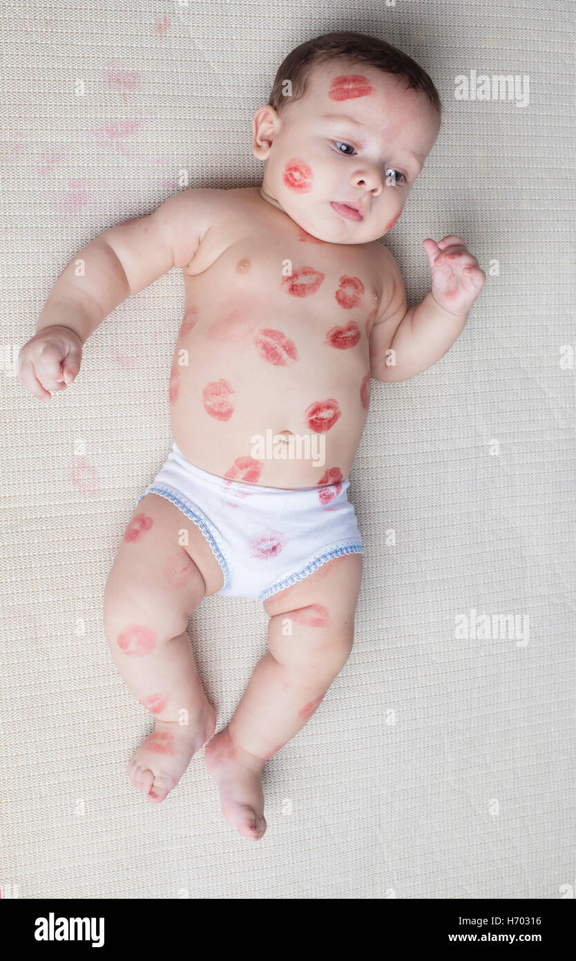 Small boy laying on fabric kissed with red lips Stock Photo
